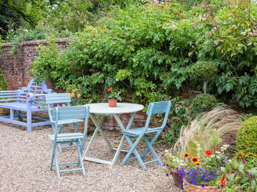 Loose decomposed granite patio with folding chairs, small table, plants, and flowers