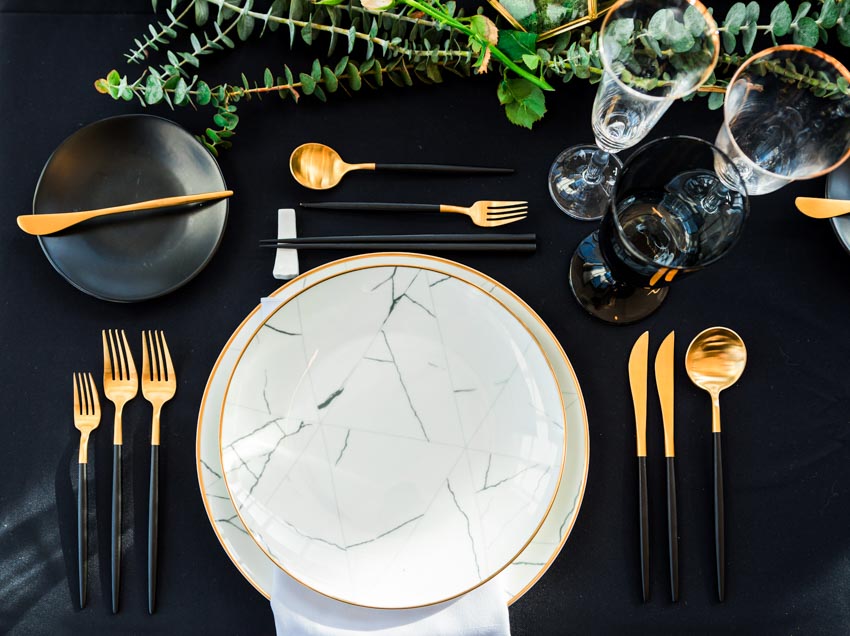 Luxurious dining setup with plates, forks, knives, spoons, saucers, and glasses