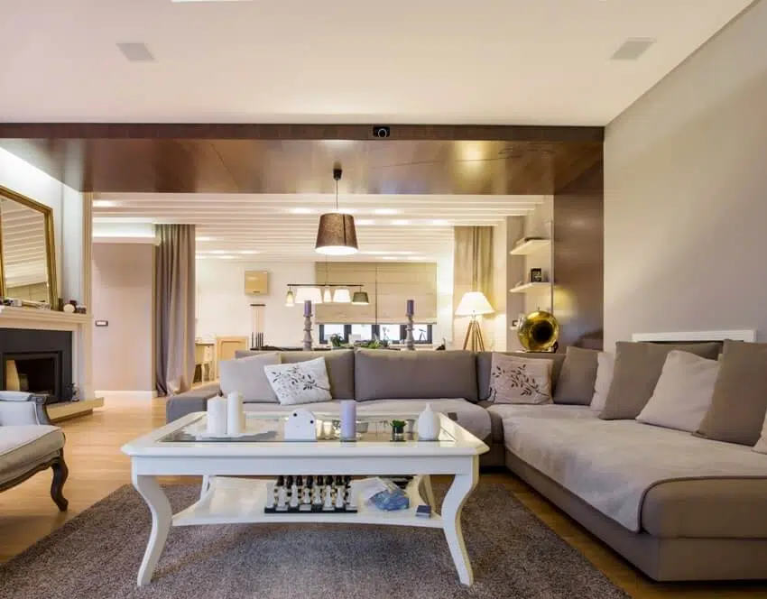 Room with corner sofa and a view of kitchen with warm lighting 