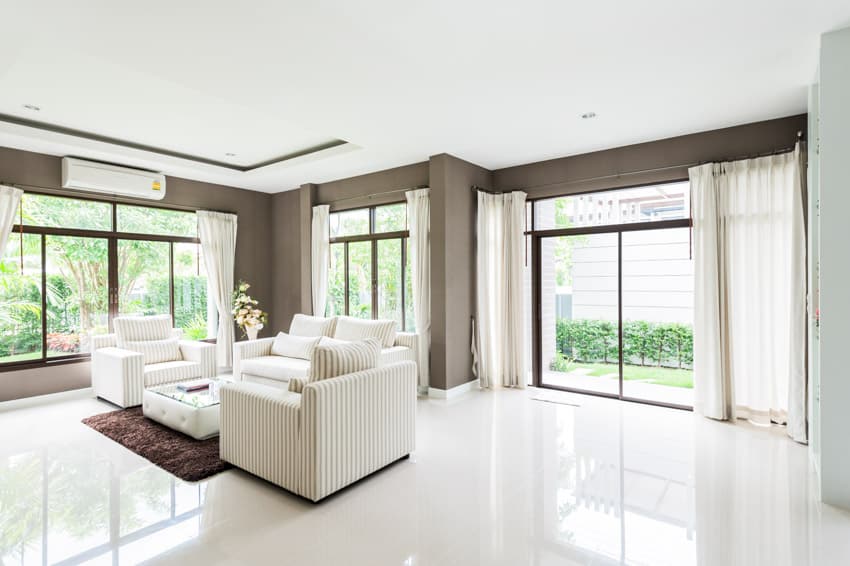 Minimalist living room with quartz slab flooring, sofa chairs, rug, air conditioner, glass windows, and door