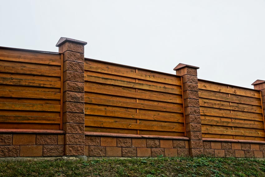 Modern horizontal fence made of wood with stone pillars