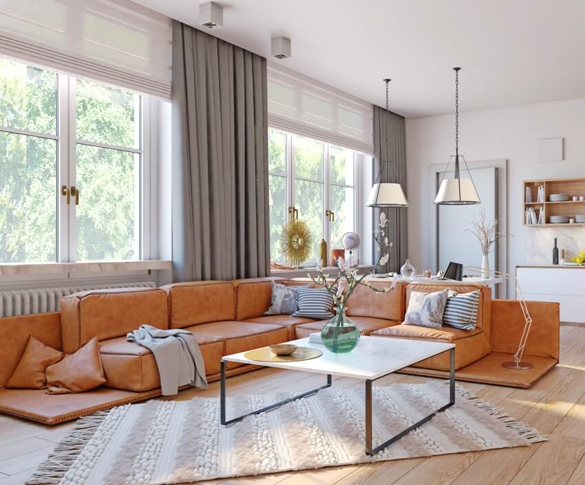 Modern living room interior with orange big floor sofa, natural lighting and windows with cotton fabric double sided curtains