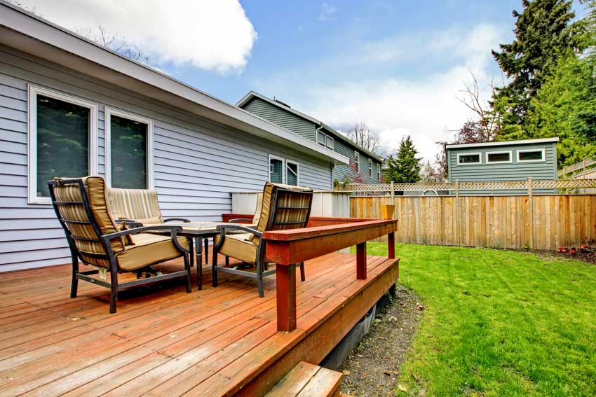 Outdoor area with cushioned chairs, table, and wood fences