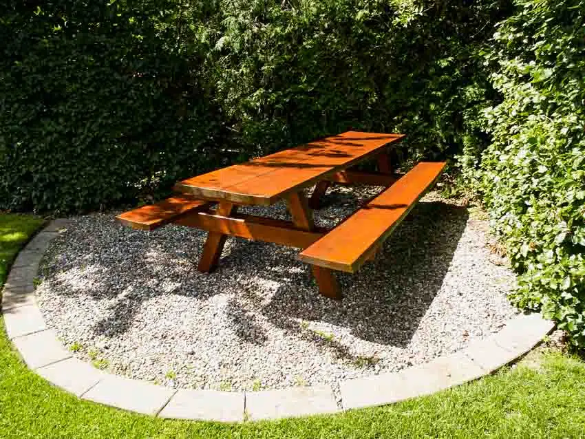 Outdoor area with decomposed granite patio, wood bench, table, and plants