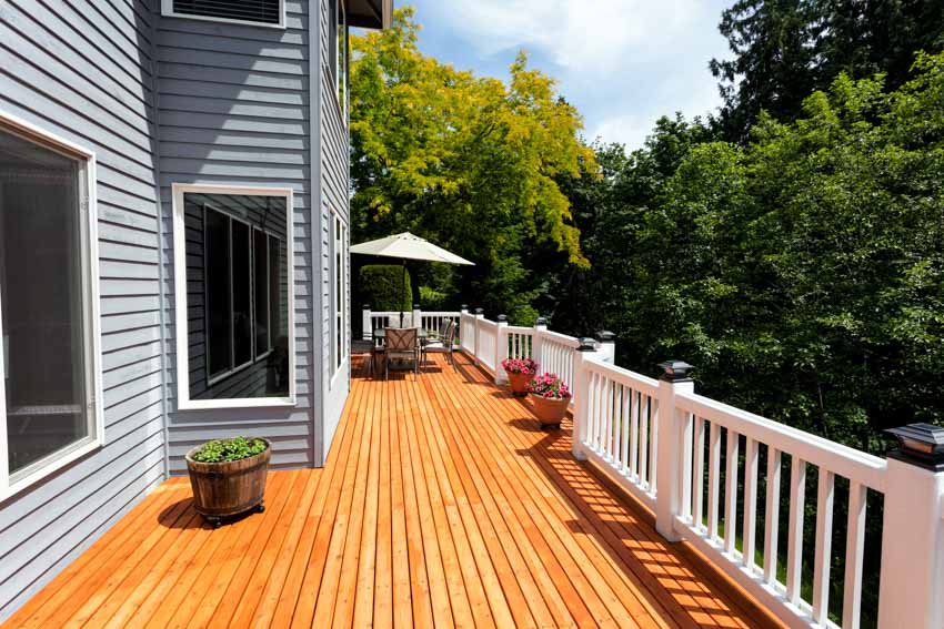 Outdoor area with house siding, glass window, redwood deck, plants, and railings