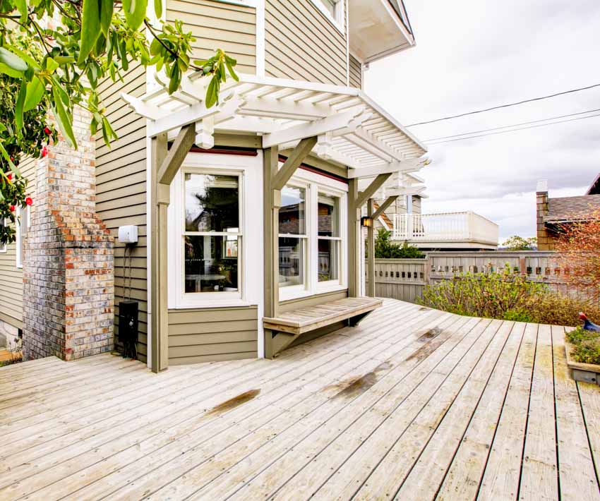 Outdoor area with pressure treated wood deck, house siding, windows, and plants