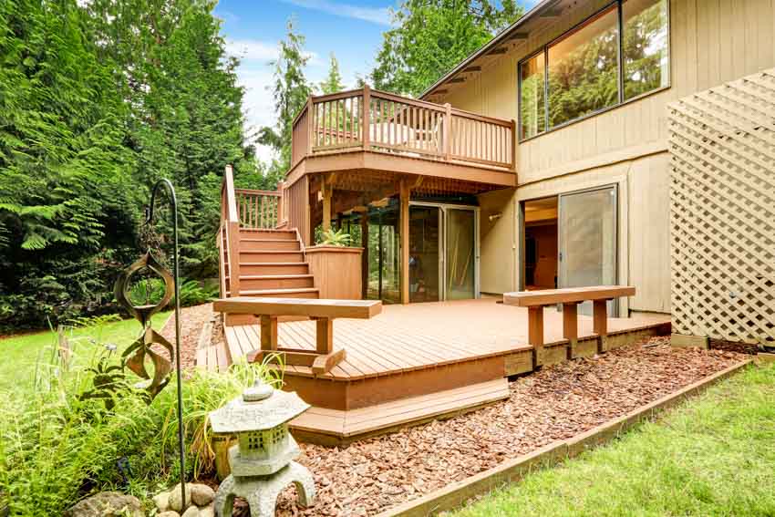 Outdoor area with pressure treated wood deck, stairs, windows glass, door, and hedge plants