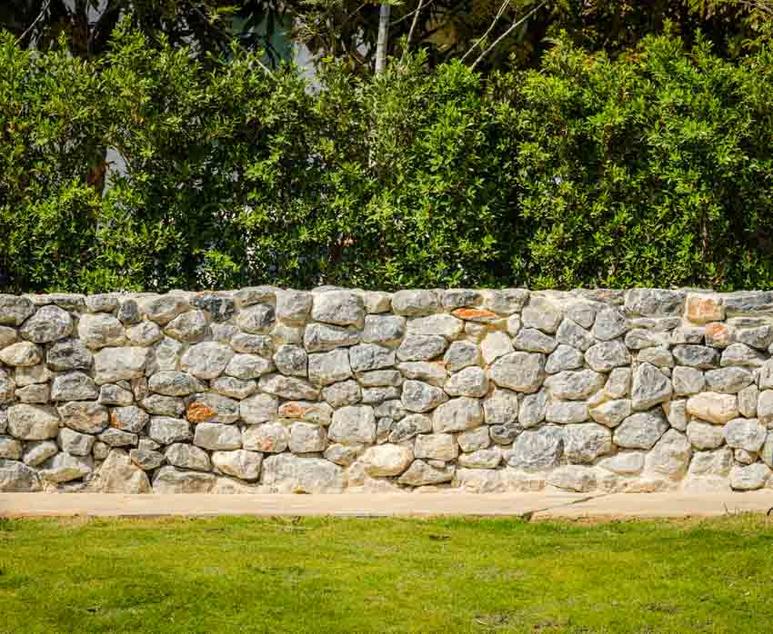 Outdoor area with stone fence and trees