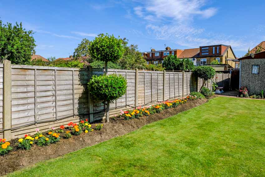 Outdoor area with wood horizontal fence, flowers, and small trees