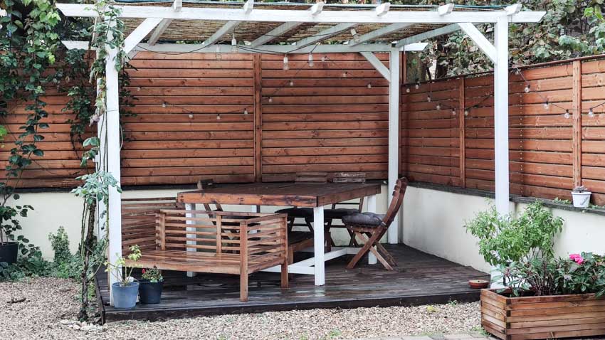 Outdoor patio with horizontal fence panels, pergola, deck, table, chairs, and plants