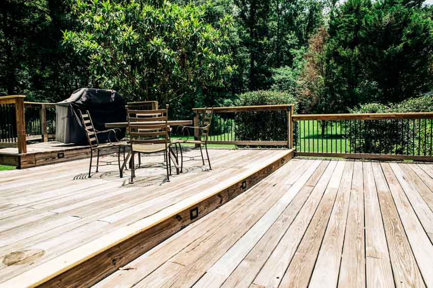 Outdoor pressure treated wood deck with table, chairs, and metal railings