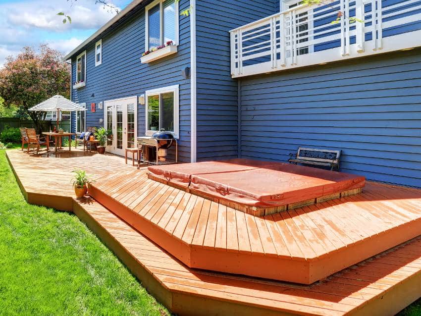 Picture perfect backyard with teak wood deck stain, umbrella covered seats and beautiful green grass