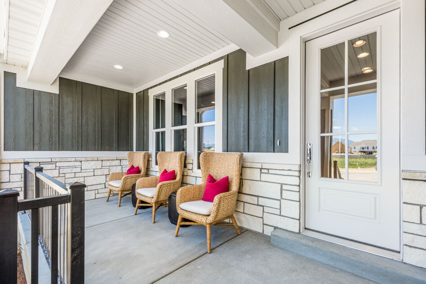 Porch with beadboard ceiling, chairs, concrete flooring, glass door, and ceiling lights
