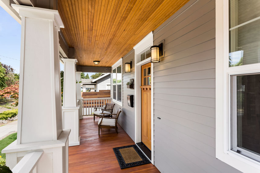 Porch with siding, wood beadboard ceiling, chair, and wall sconces