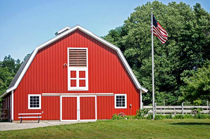 Red barn with gable roof, windows, door, and flagpole