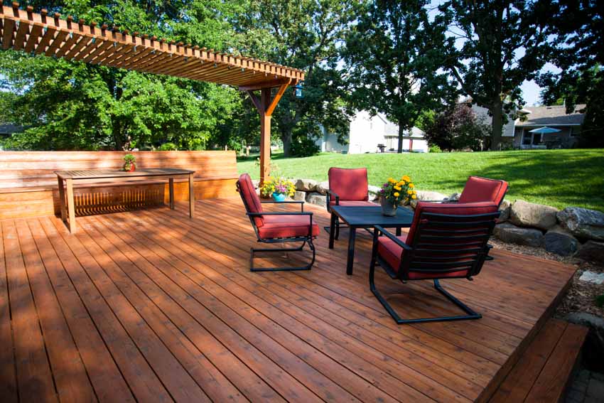Redwood deck with cushioned chairs, table, and pergola