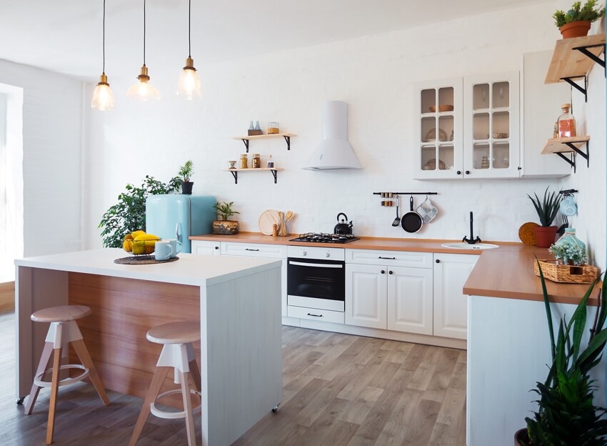 Scandinavian kitchen interior features freestanding kitchen island with stools, white cabinets, and wooden countertops