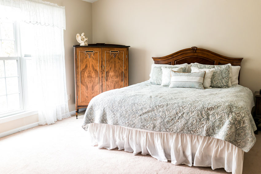 Simple bedroom with bed skirt, comforter, cabinet, headboard, and windows