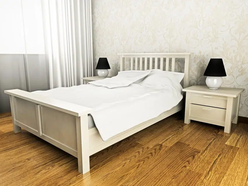 Simple bedroom with wood floor, bed headboard, footboard, nightstand, lamp, and curtain