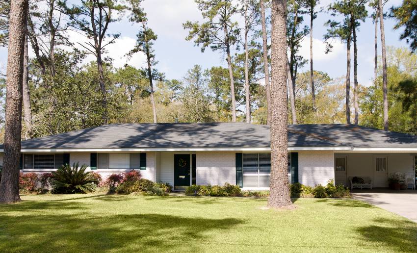 A simple ranch style home with wide front yard and big trees