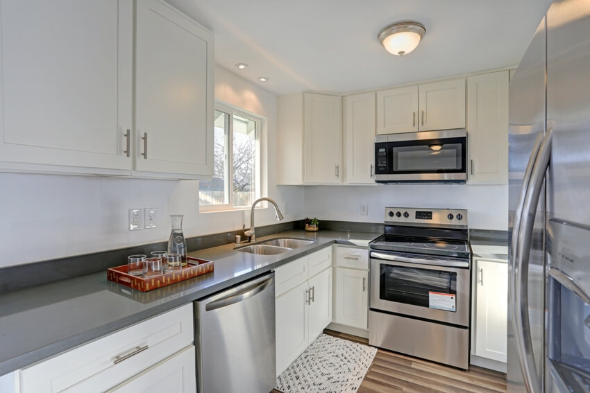Small kitchen without backsplash features stainless steel appliances, granite countertop, and white cabinets