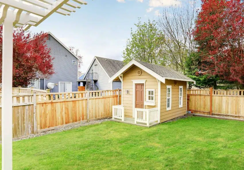 A small wooden shed in the back yard with Douglas fir for fence