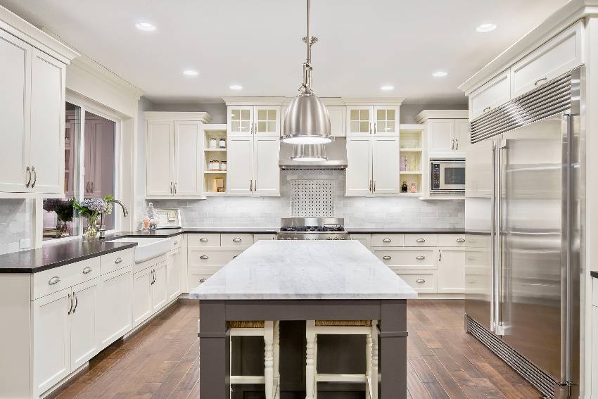 A spacious kitchen with white inset cabinets, kitchen island, stainless steel appliances and hardwood floors