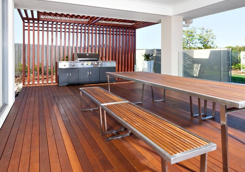 Stained Douglas fir deck with wooden benches and table and a modern silver color gas grill cabinet with side burners