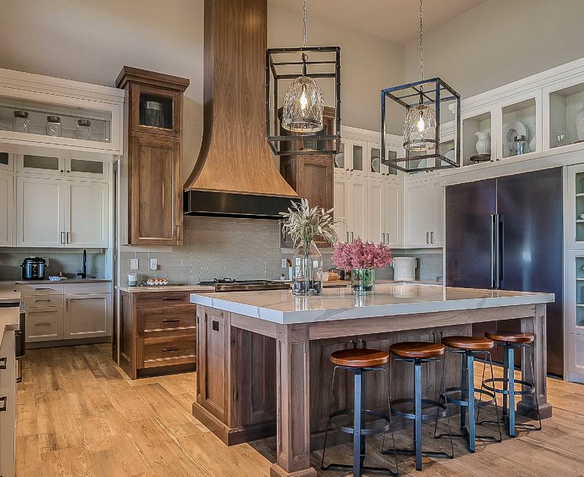 Stunning custom kitchen with caged chandeliers, oversized fridge, vent hood and wooden island with stools