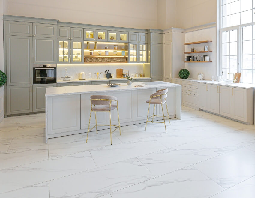 Stylish modern kitchen in white and pastel colors with large format tiles, island and elegant chairs and some kitchen accents
