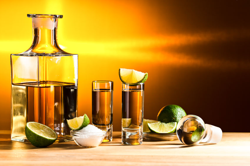 Tequila decanter with shot glasses and lemon slices