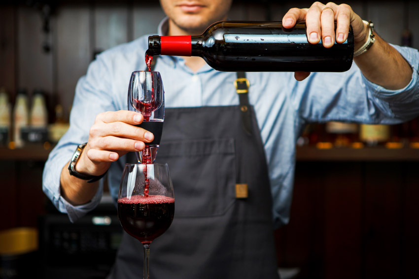 Waiter pouring wine into aerator and decanter