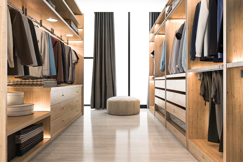 Walk in closet with LED lighting fixture, polished floor, ottoman, and windows