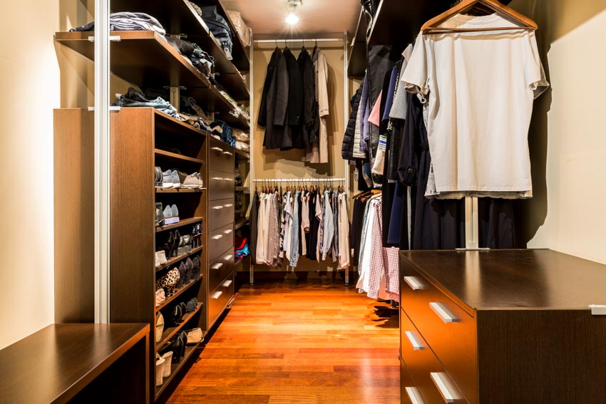 Walk-in closet with lighting fixtures, wood floor, shelves, and drawers