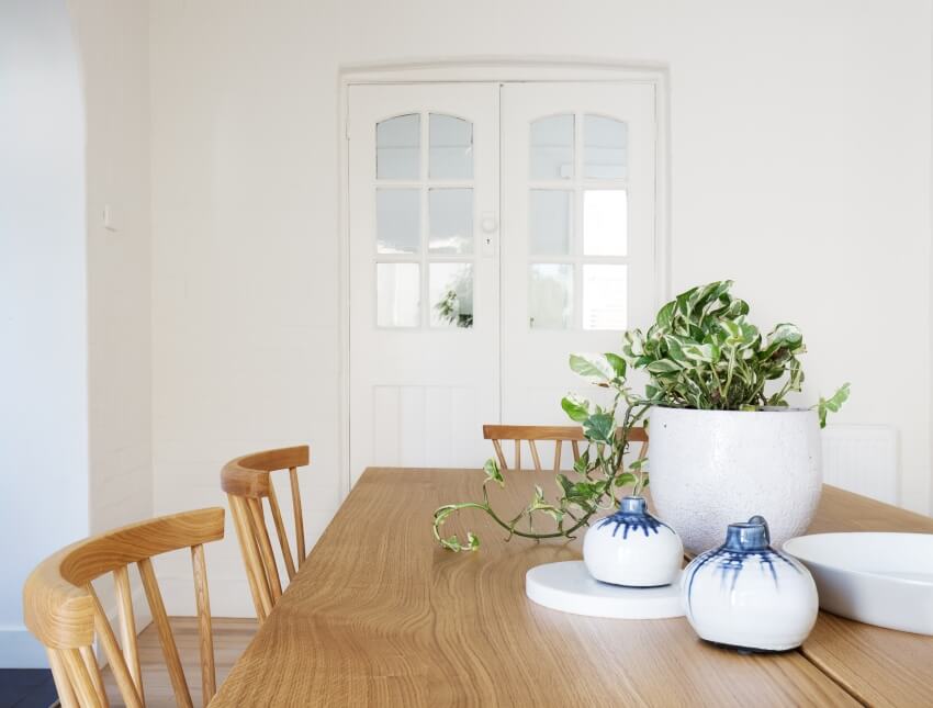 A white dining space with wooden dining set and french doors