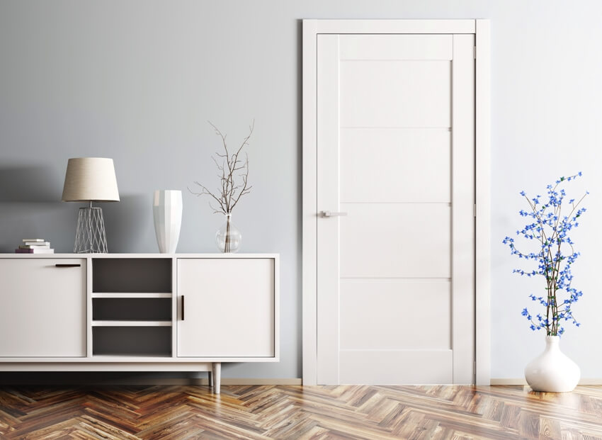 White, gray and wooden interior with pre hung door, potted pot on floors and a lamp placed on white console table