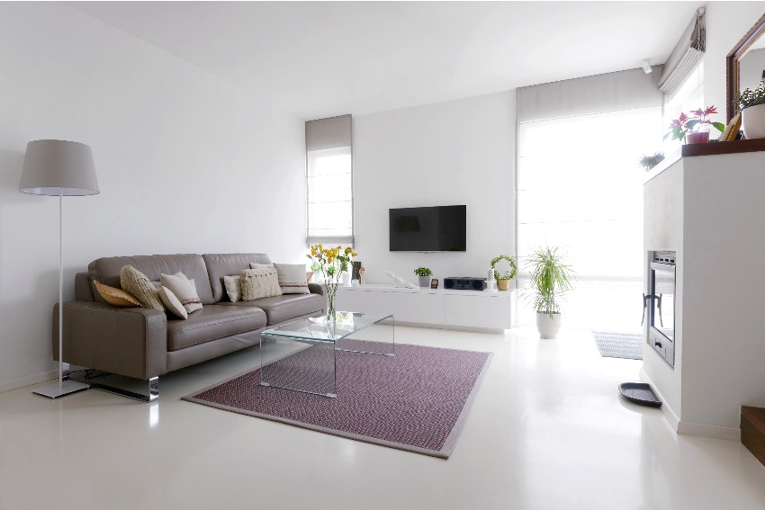 White living room with glass table, quartz epoxy floors and taupe leather sofa and carpet
