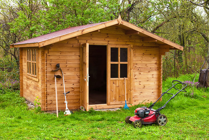 Backyard wooden shed with lawn mower
