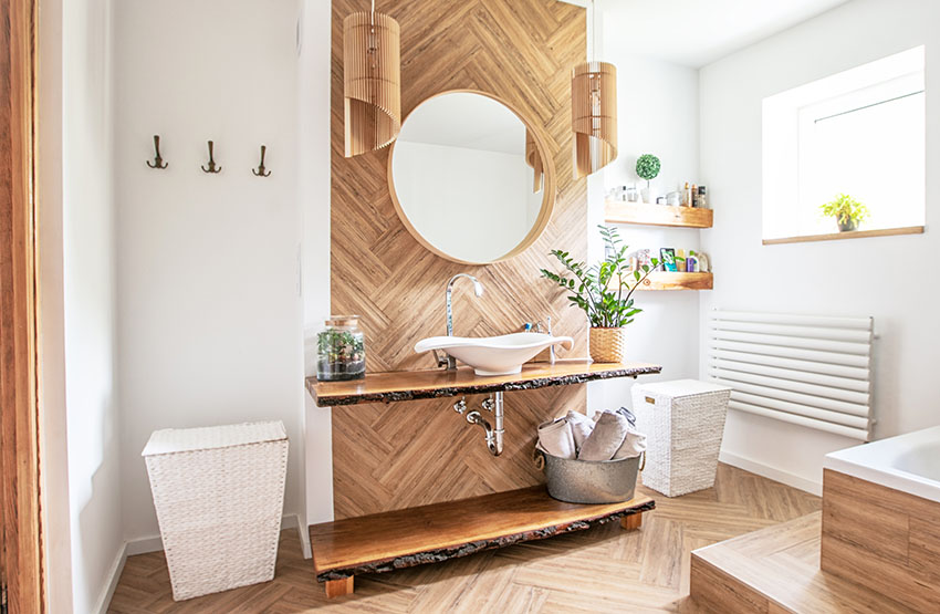 Boho styles bathroom interior with live edge wood shelves with sink herringbone floor and accent wall round wirror laundry baskets round mirror with wooden frame towel hook