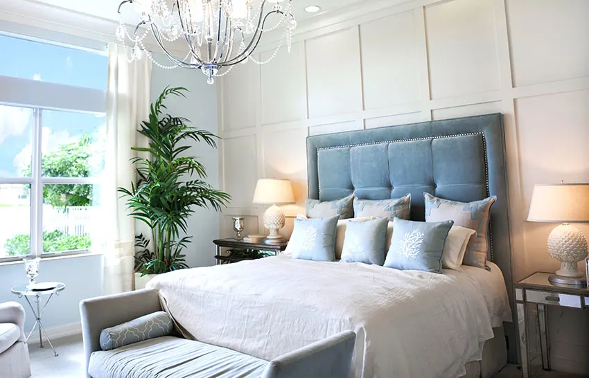 Bedroom with plush bed pillows chandelier bedside tables with lamp shades indoor plant board and batten wall