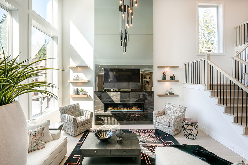 Elegant living area with black mantle, electric fireplace, modern stool, and coffee table with antique display