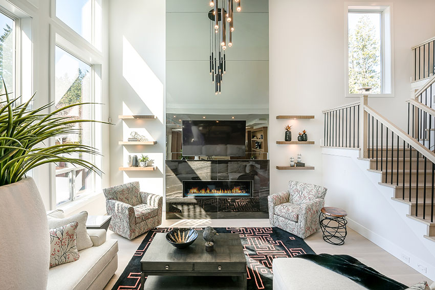 Living area with black mantel, fireplace, bespoke chandelier and staircase