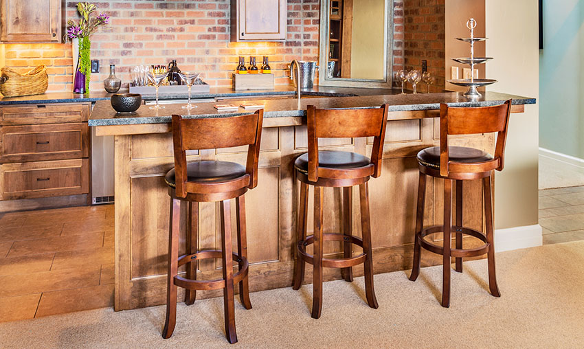 Rustic kitchen with bar counter wooden stools brick wall carpet flooring