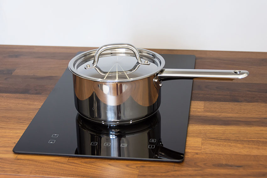 Small stainless saucepan induction stove wooden countertop