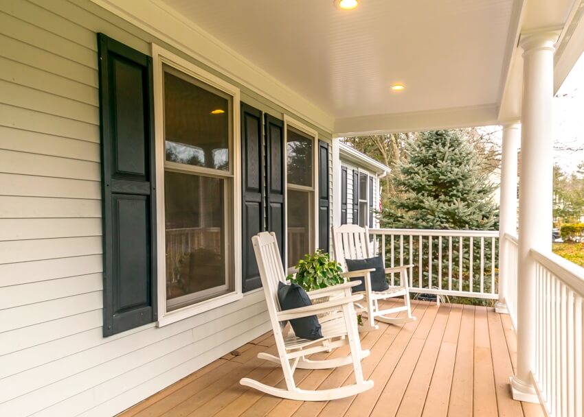 A quiet porch of a white suburban home with window shutters