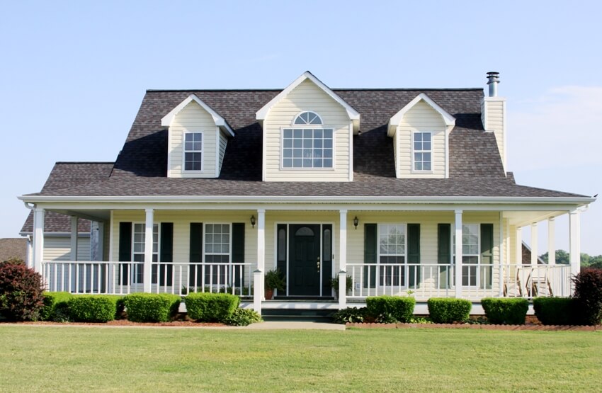 American home country farmhouse style painted with cream colored exterior featuring window shutters on the ground floor 