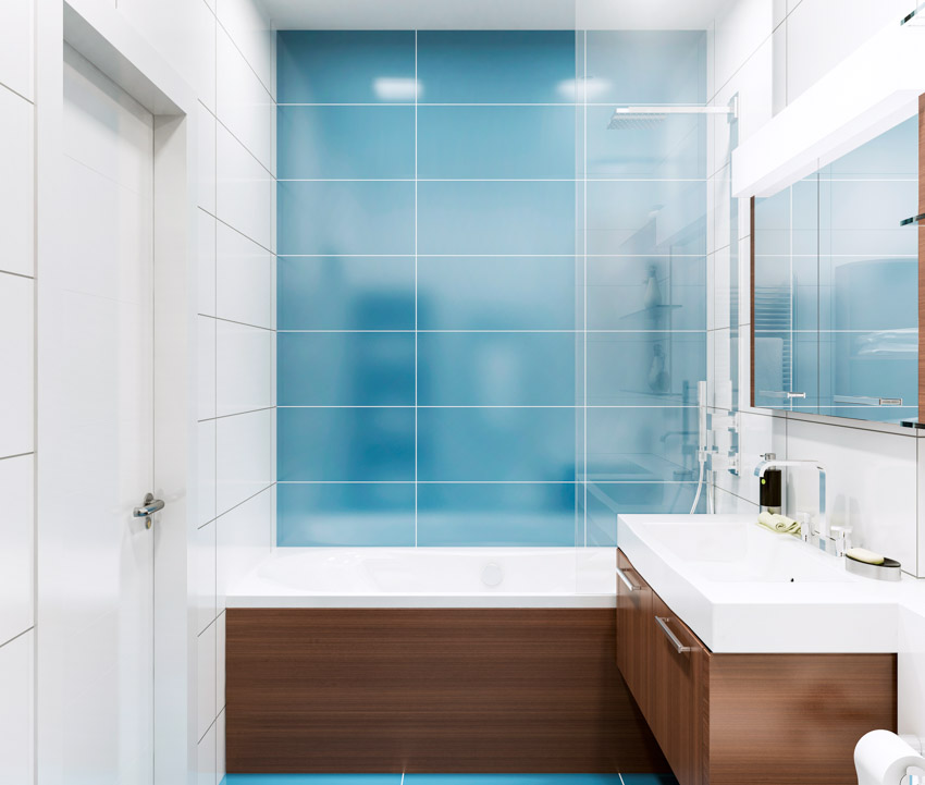 Bathroom with blue glass tile shower, tub, vanity, wood cabinet, sink, and mirror