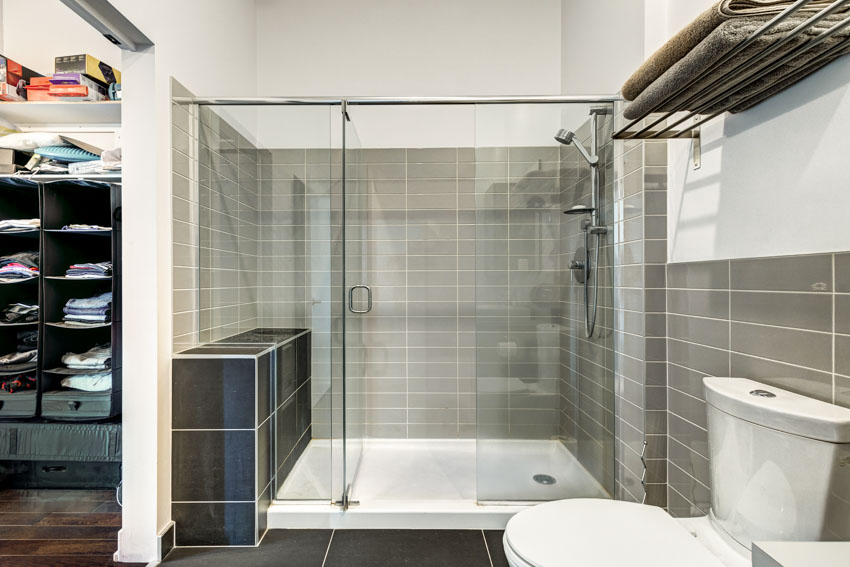 Bathroom with glass door, towel holder, toilet, and glass tile shower