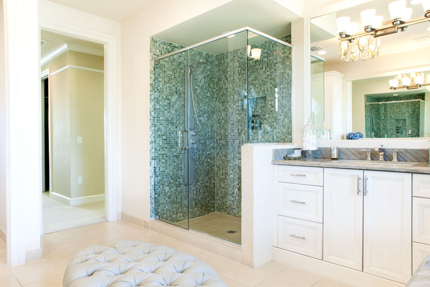 Bathroom with shower space, cabinets, countertop, mirror, and floor rug