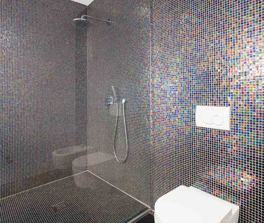 Bathroom with glass mosaic tile shower wall, glass divider, and toilet